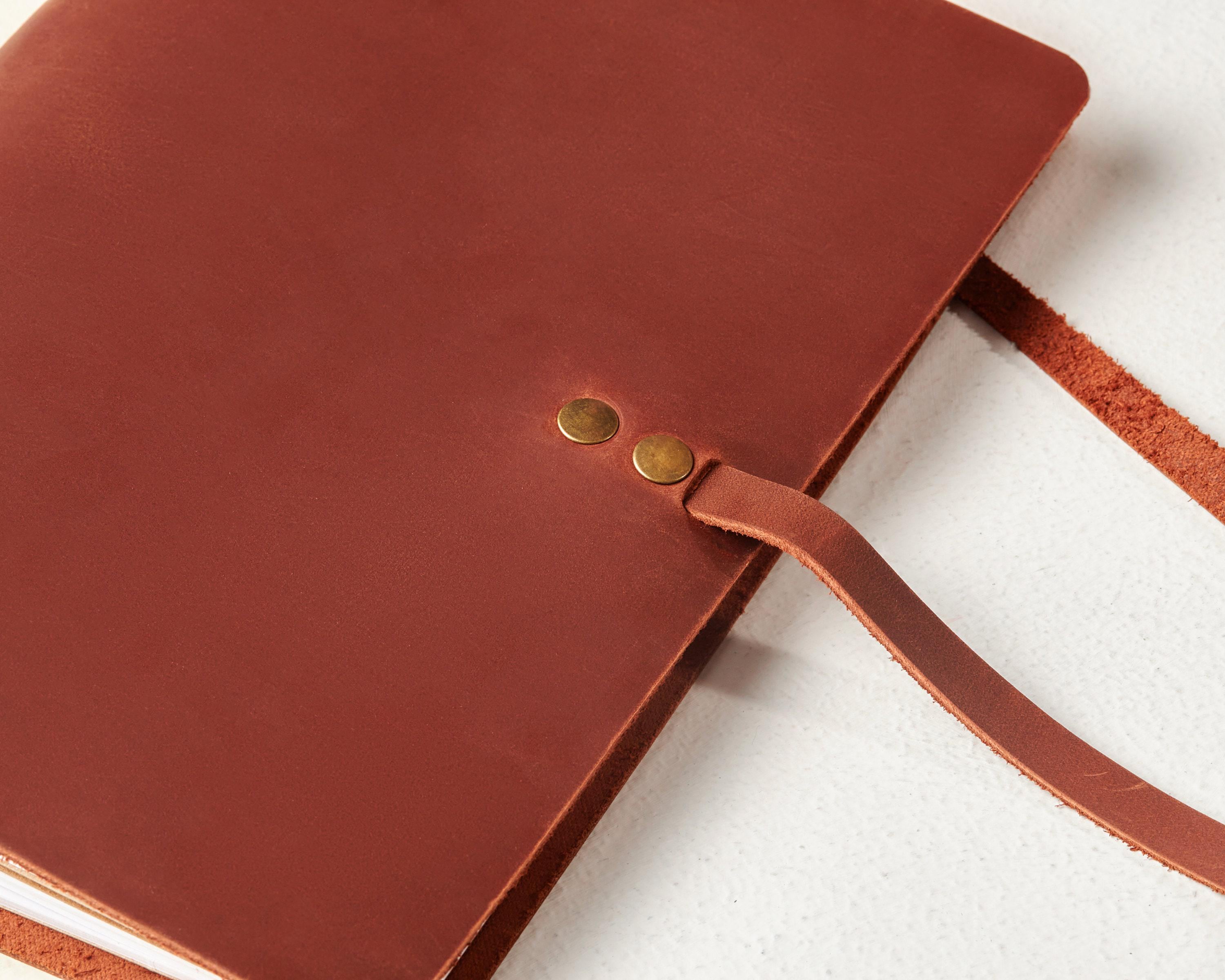 a brown leather notebook with a brown strap