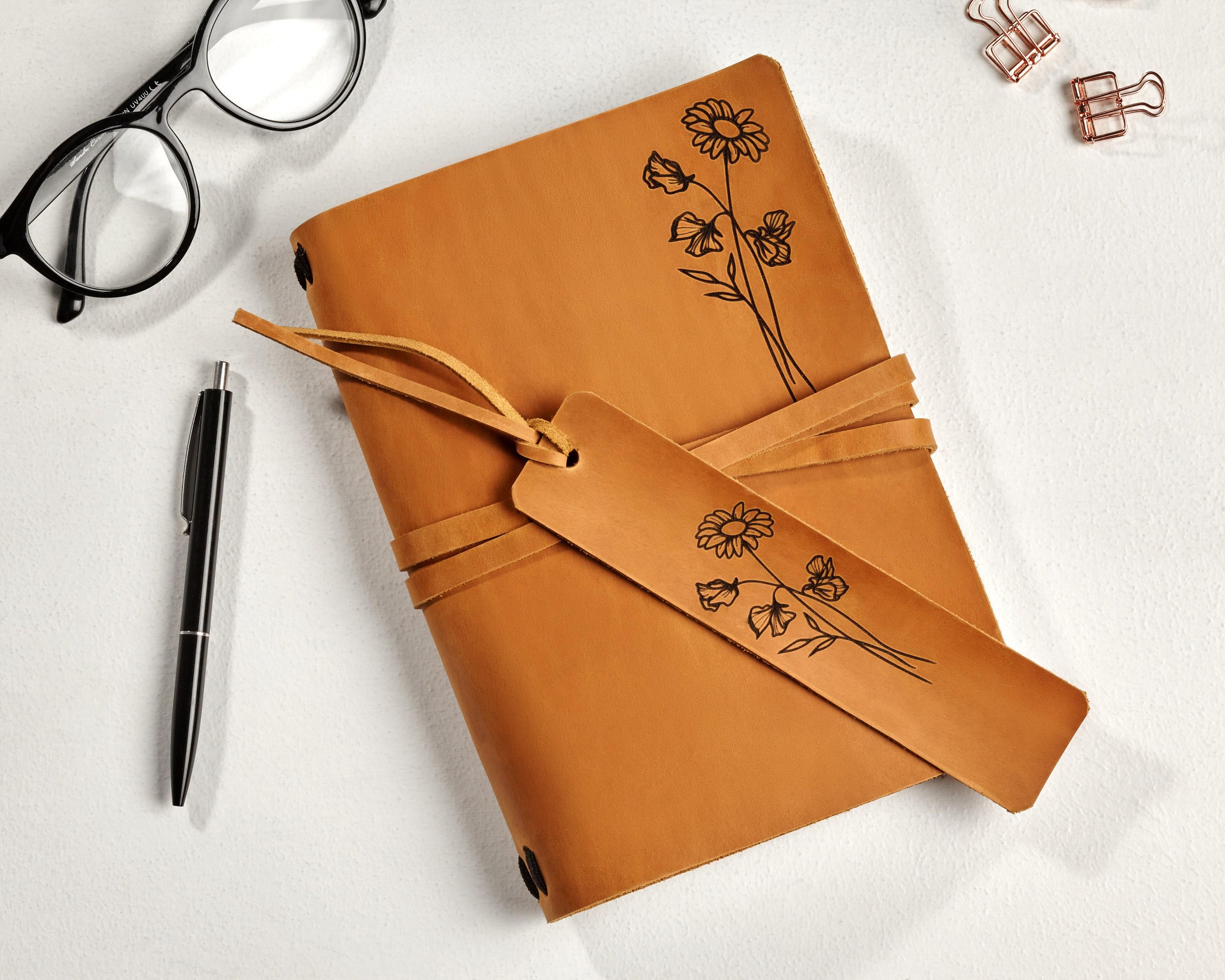 a notebook with a flower drawn on it next to a pair of glasses